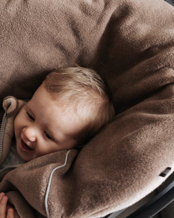 Lapsi istumassa ruskeassa Brave Bear -turvaistuinviitassa turvaistuimessa.