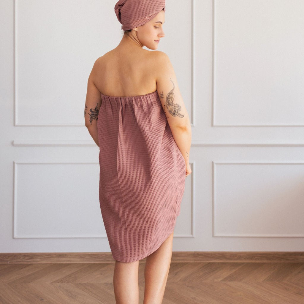 Naisen päällä kietaisypyyhe, jonka väri on vanha roosa.