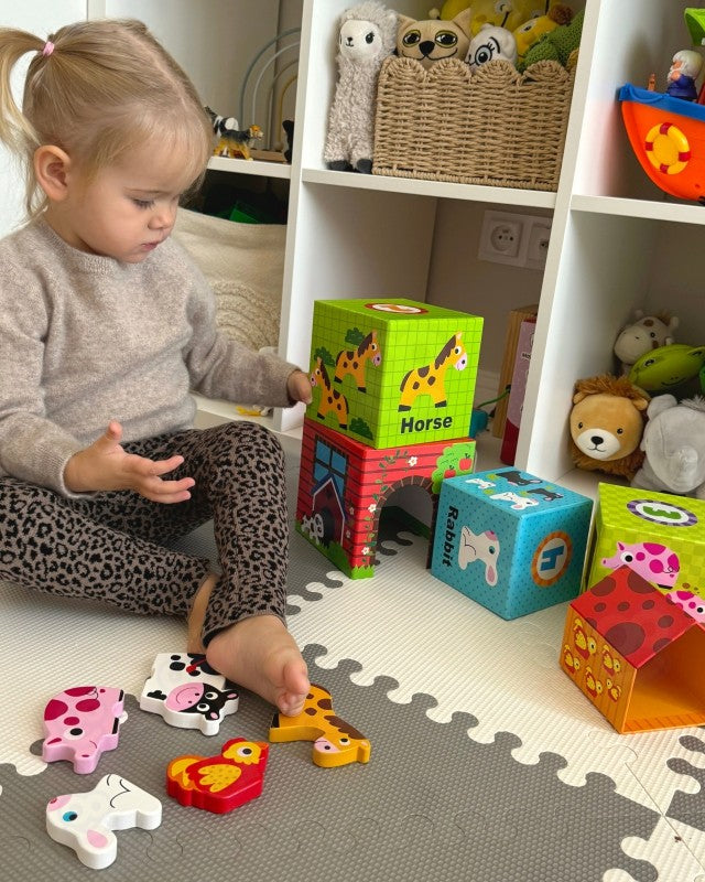 Lapsi leikkii värikkäällä puupalikoista rakennetulla maatilan palikkatornilla, mukana puisia eläinhahmoja – opettavainen palapeli 1–3-vuotiaalle.