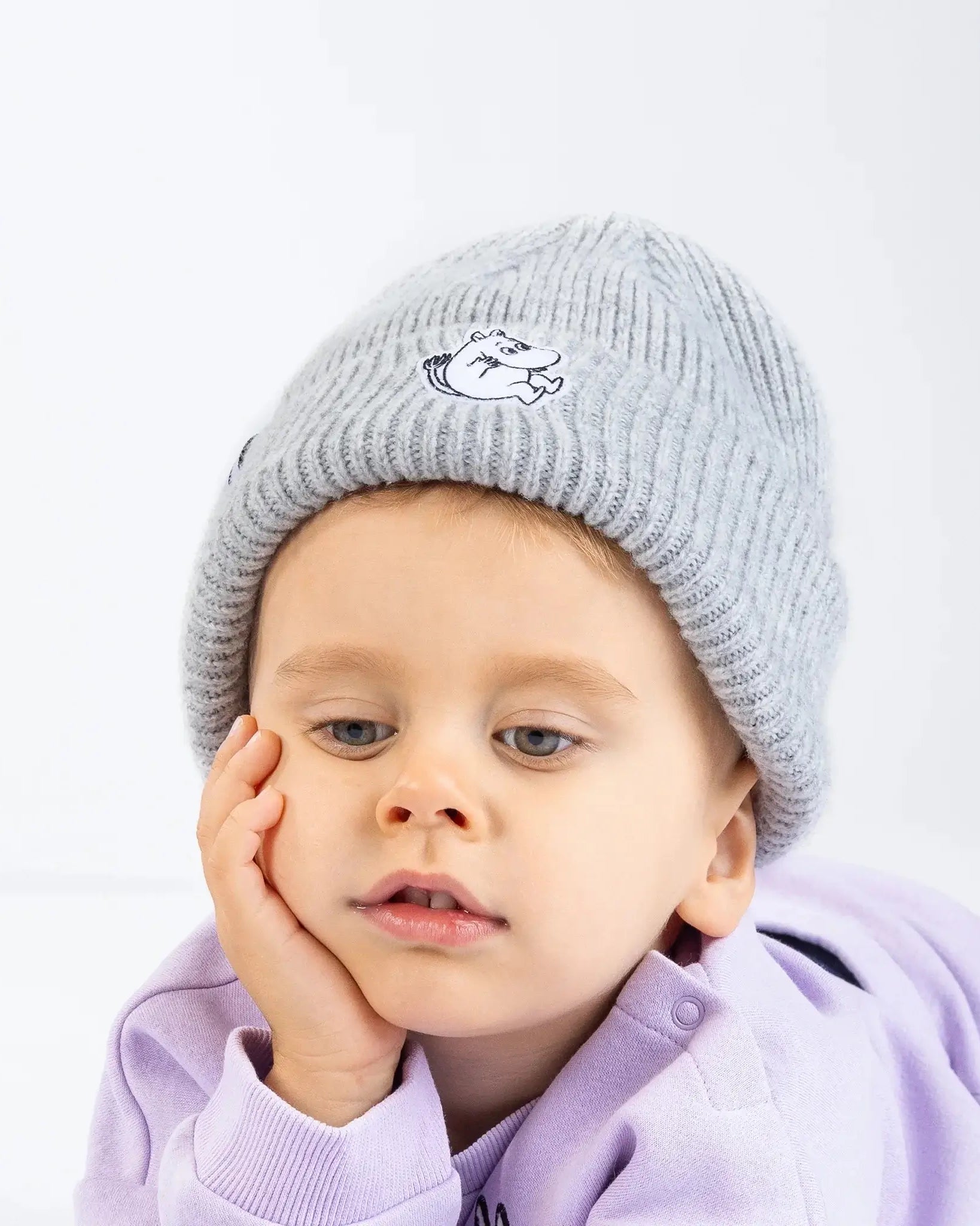 Lapsella päässä harmaa pipo jossa muumipeikon kuva