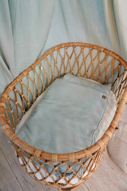 Musliininen vauvan peitto ja tyynysetti mintun sävyssä vauvan rottinkisessa vauvan sängyssä